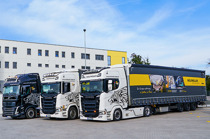 Drei LKW der Firma Wolfmüller stehen vor dem Firmengebäude